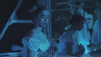 Two ballerinas are warming up and rehearsing movements backstage on stage. Preparation for the performance video