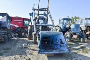 Open-air garage for agricultural machinery. Old tractors, combines and towed equipment photo