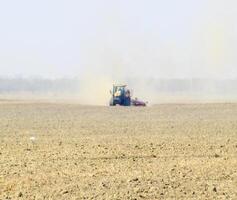 Tractor rides on the field and makes the fertilizer into the soi photo