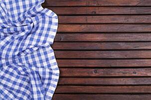 Dark wooden table with blue checkered tablecloth, top view with copy space photo