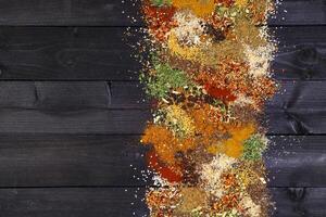 Herbs and spices over black wooden background photo