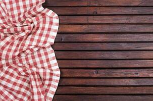 Red checkered tablecloth on dark wooden table with, top view with copy space photo