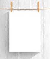 Empty sheet of paper hanging on the clothesline over wooden background. Mock up for your project with copy space photo