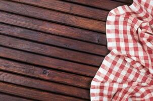 Red checkered tablecloth on dark wooden table with, top view with copy space photo