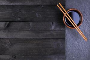 Background for sushi. Soy sauce, chopsticks on black stone. Top view with copy space photo