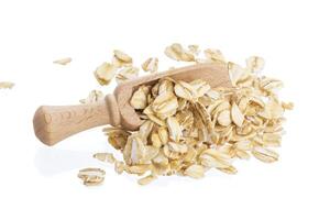 Oat flakes in wooden scoop isolated on white background. Close up. photo