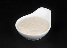 Horseradish sauce in white bowl isolated on black background photo