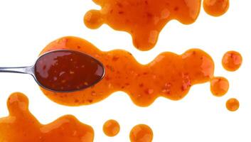 Splach of sweet and sour sauce with spoon isolated on white background. Top view photo