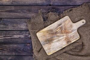 Wooden table with burlap cloth and cutting board photo