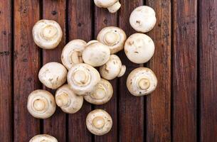 Mushrooms champignon on wooden background. Top view. Copy space. photo