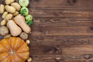 vegetales en de madera antecedentes. calabaza, calabacín, papas, cebollas y otro verduras, parte superior vista, Copiar espacio foto