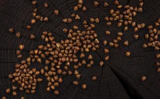 Heap of buckwheat grain on black wooden background. Top view photo