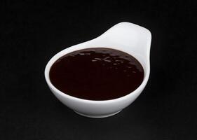 Barbecue sauce in white bowl on black background photo