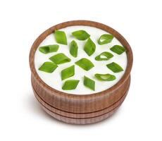 Sour cream and green onion in wooden bowl isolated on white background photo