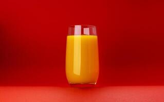 Glass of orange juice isolated on red background with copy space photo