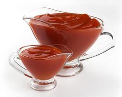 Glass bowls of ketchup isolated on white background photo