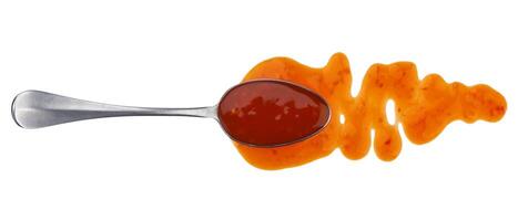 Sweet and sour sauce with spoon isolated on white background. Top view photo