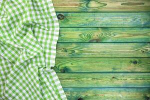 Green checkered tablecloth on wooden table, top view, copy space photo