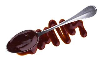 Splashes and spilled barbecue sauce with spoon isolated on white background. Top view photo