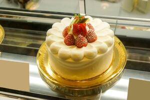 vainilla hielo crema pastel con fresa congelado en parte superior y vender en el panadería tienda. foto