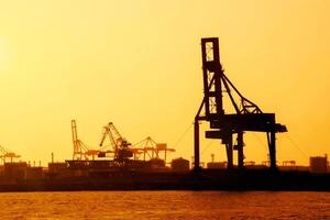 Silhouette of container crane are loading at Osaka port evening and gantry crane working background. photo