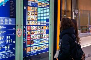 Osaka City, Japan, 2023 - Chinese woman tourists looking and find restaurant at the terminal electronic map board in Kansai International airport photo