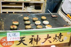Osaka City, Japan, 2023 - Mochi grill on hot pan with Japanese name and price label. One of tourist popular snack at Kuromon market ,Osaka city, Japan. photo