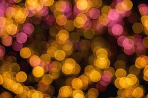 Closeup abstract blurred and bokeh of reflection lighting of pink and yellow led light bubs on black background. photo