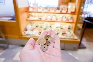 Closeup Japan Yen coins on hand front of blurry Japanese restaurant display, photo