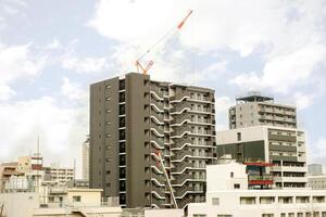 Hoisting cranes working on building and cityscape view in urban city and on bright blue sky with cloud background. photo