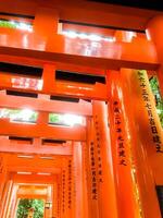 KYOTO, JAPAN, 2023- Look up view red wooden poles of Torii gates at Fushimi Inari Shrine in Kyoto. This is Shinto shrine and one of the most popular tourist destinations in Japan. photo