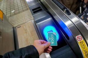 Osaka ciudad, Japón, 2023 - de cerca mano de personas utilizando Japón ic tarjeta icoca toque y pagar a Entrada automático boleto máquinas a numba subterraneo estación. foto