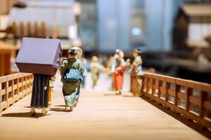 Osaka City, Japan, 2023 - Miniature models and toys in activities and daily life of 1800's ancient Japanese people on wooden bridge in the city. photo
