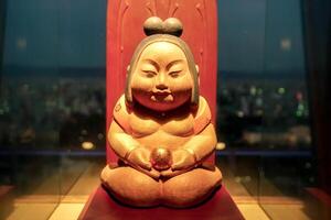 Osaka City, Japan, 2023 - Wooden Japanese baby god Billiken Enshrined on the 5th floor of the Tsutenkaku tower. Billiken is a charm doll and popular symbol of happiness, good luck of Osaka. photo