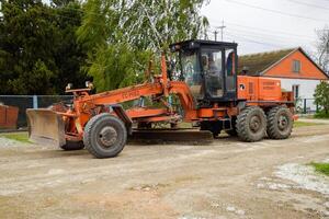 calificador en un suciedad grava la carretera. calle reparar por agregando escombros. foto