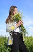 Young beautiful girl with a bouquet of chamomiles. A woman in a barley field photo