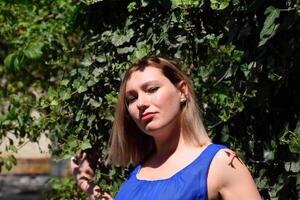 Portrait of a girl in a blue dress on background of green arbor of ivy. photo