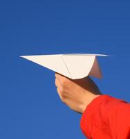 blanco papel avión en mano en contra el cielo. un símbolo de libertad en el Internet foto