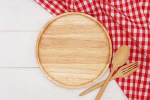 Empty round wooden plate with spoon and fork on white wooden table. Top view image. photo