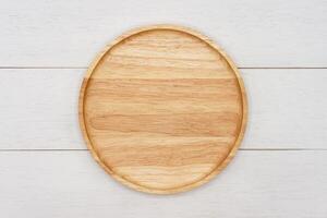Empty round wooden plate on white wooden table. Top view image. photo