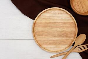 vacío redondo de madera plato con cuchara y tenedor en blanco de madera mesa. parte superior ver imagen. foto
