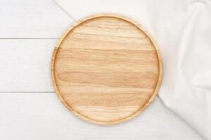 Empty round wooden plate on white wooden table. Top view image. photo