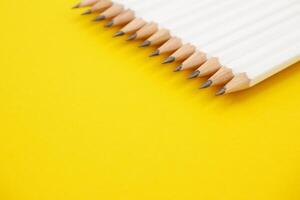 White pencils on yellow background with copy space. photo