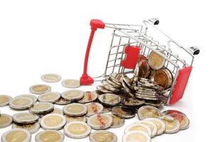 Red miniature shopping cart filled with new 10 Thai Baht coins, isolated on white background. Business concept. photo