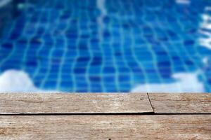 Empty rustic wooden table in front of blurred background of swimming pool. photo