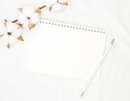 blanco blanco espiral cuaderno con blanco lápiz en cama. foto