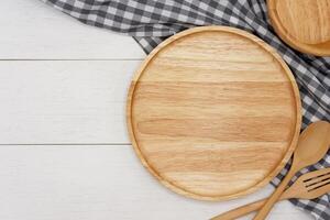 Empty round wooden plate with spoon and fork on white wooden table. Top view image. photo