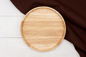 Empty round wooden plate on white wooden table. Top view image. photo