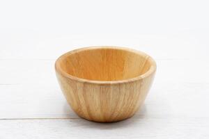 Empty round wooden bowl on white wooden table. photo