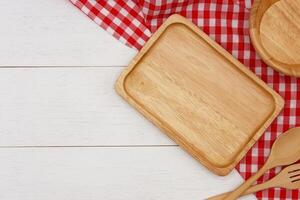 Empty rectangle wooden plate with spoon and fork on white wooden table. Top view image. photo
